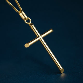 A Golden Silver Classic Cross Pendant, photographed against a dark navy blue background.