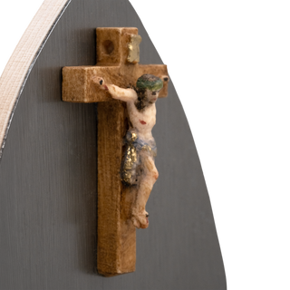 A small wooden crucifix with a detailed figure of Jesus Christ, mounted on a Teardrop-shaped silver-toned metal wall-mounted holy water font 