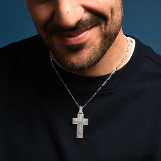 Man wearing a black sweater with a Sterling silver Crucifix Pendant against a blue background