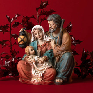 Decorative nativity scene with Mary, Joseph, and baby Jesus on a red background 