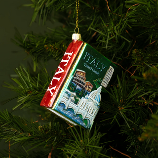 Christmas ornament shaped like a travel guide book about Italy on a tree.