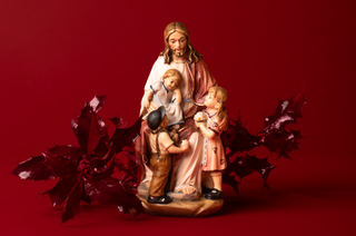 Wooden statue of jesus with children on a red background