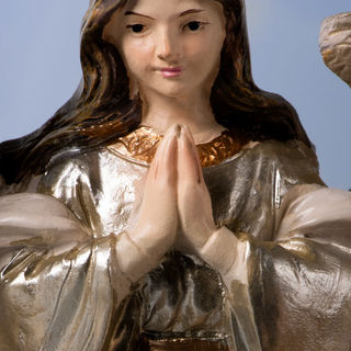 close-up of resin nativity scene: statue of a angel with hands clasped in prayer against a blue sky