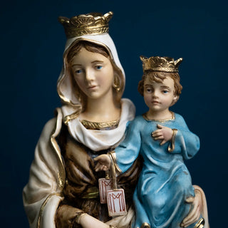 Our Lady of Mount Carmel hand-painted resin statue. A religious figurine of the Virgin Mary holding the infant Jesus, both wearing gold crowns. Mary is dressed in white and brown robes with gold trim, and Jesus is in a blue robe with gold trim, set against a dark navy background.