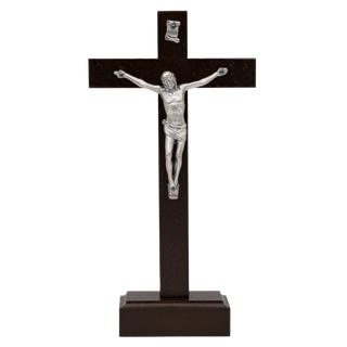 A dark brown wooden crucifix with a silver metal corpus of Jesus Christ and a small silver medal at the top